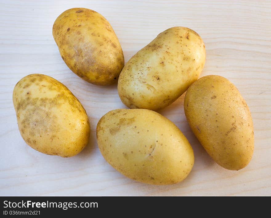 Yellow potato tubers on a wooden board. Yellow potato tubers on a wooden board