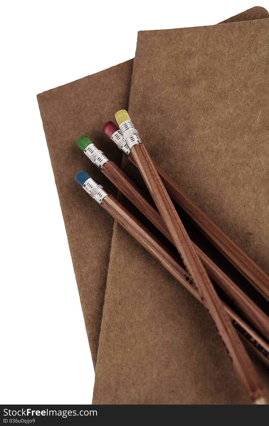 Automatic colored pencils on top of a plain brown notebook-isolated. Automatic colored pencils on top of a plain brown notebook-isolated.