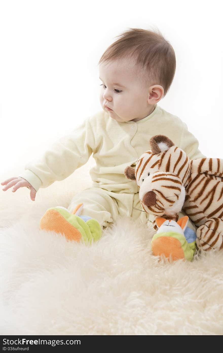 Lovely brown-eyed baby sits lies on white fur. Lovely brown-eyed baby sits lies on white fur