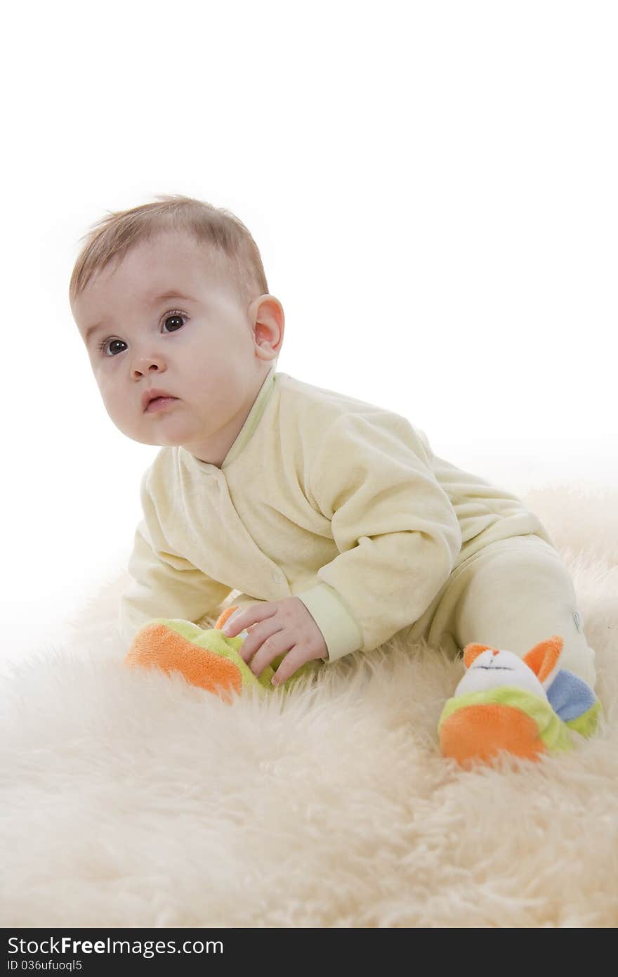 Lovely brown-eyed baby sits lies on white fur. Lovely brown-eyed baby sits lies on white fur