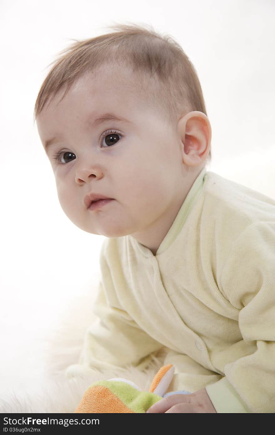 Lovely brown-eyed baby sits (lies) on white fur. Lovely brown-eyed baby sits (lies) on white fur