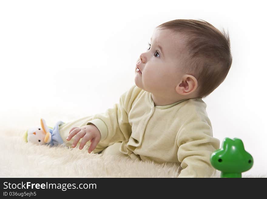 Lovely brown-eyed baby sits (lies) on white fur. Lovely brown-eyed baby sits (lies) on white fur