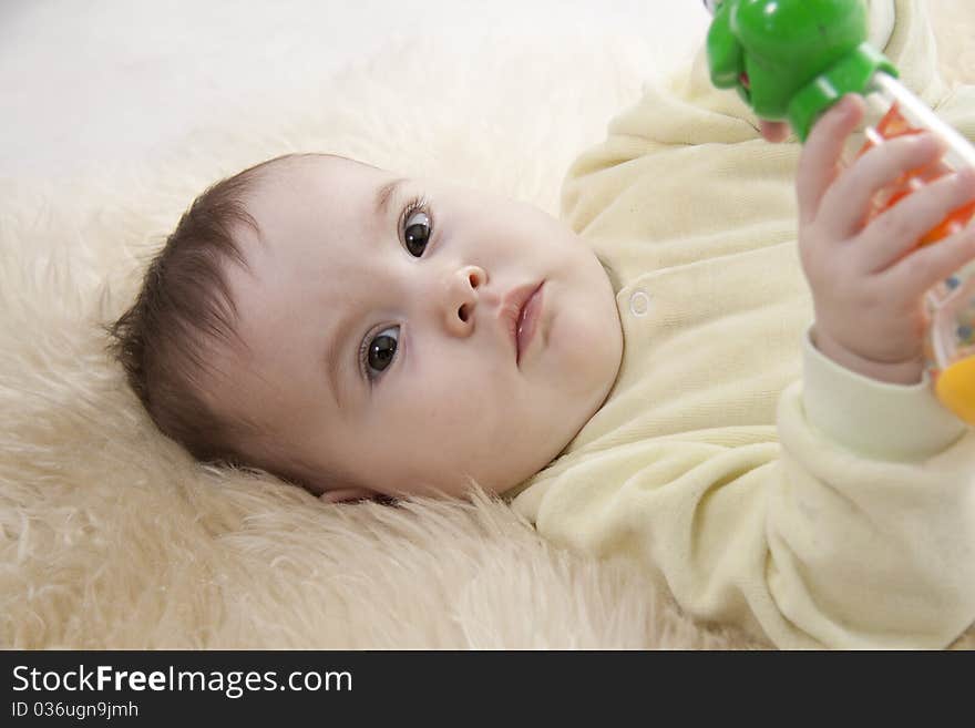 Lovely brown-eyed baby lies on white fur. Lovely brown-eyed baby lies on white fur