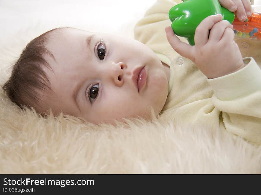 Lovely brown-eyed baby lies on white fur. Lovely brown-eyed baby lies on white fur