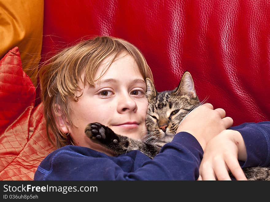 Young boy is hugging his cat at the sofa