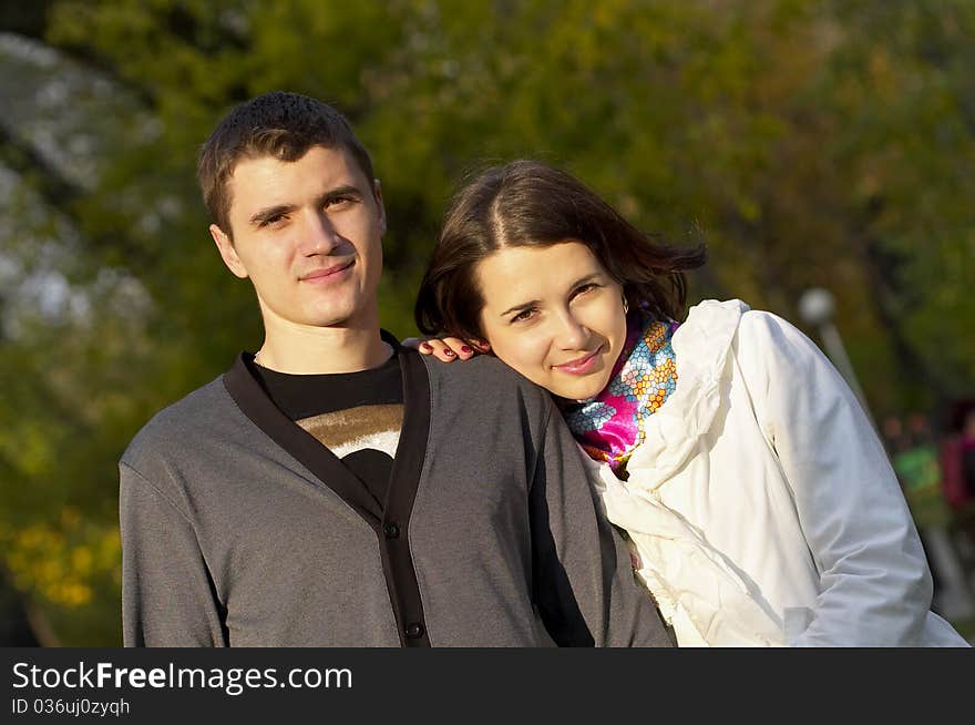 Young couple portrait over defocused autumn park background. Young couple portrait over defocused autumn park background