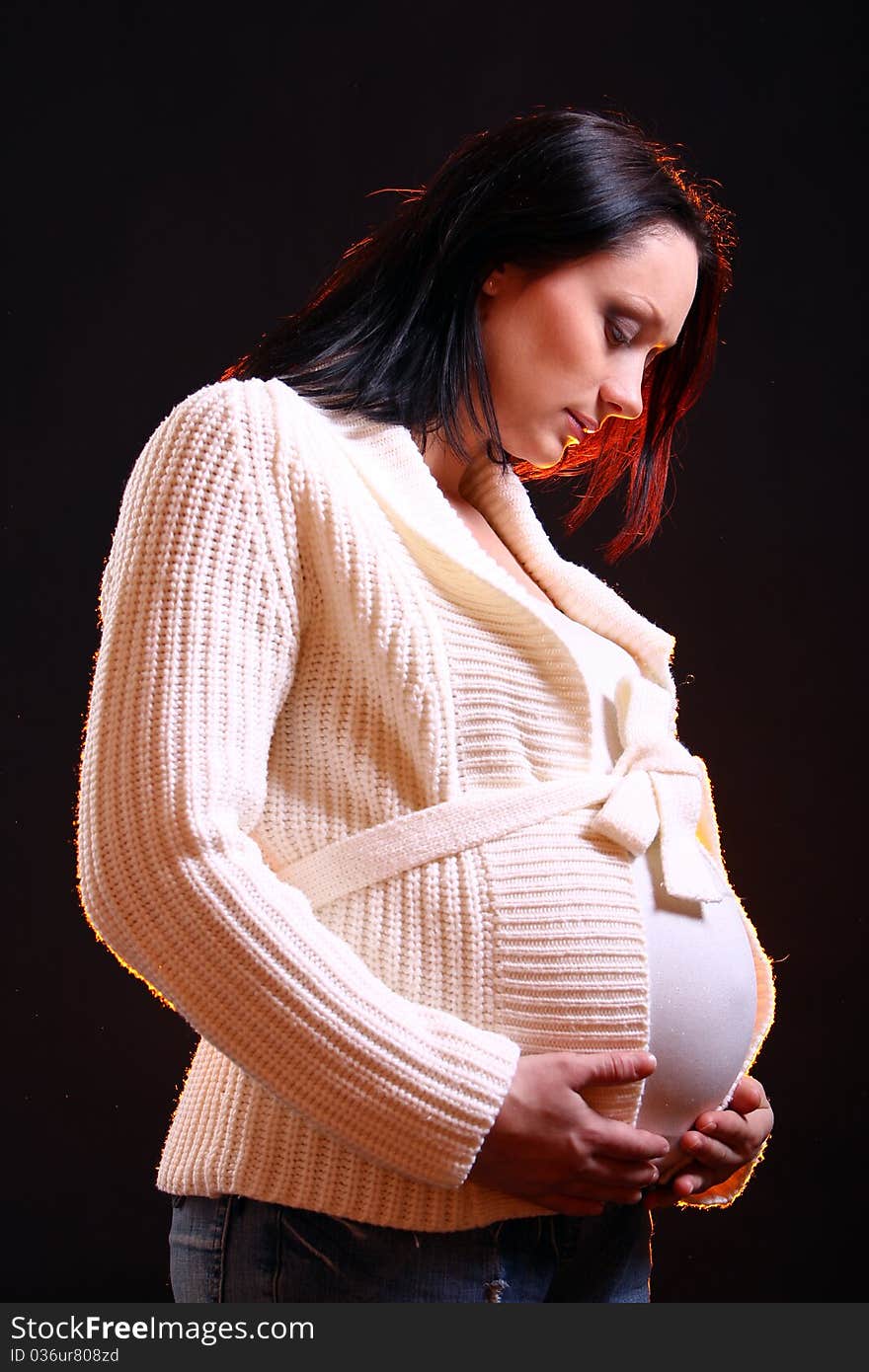 Young and beautiful pregnant woman on black background with smoke