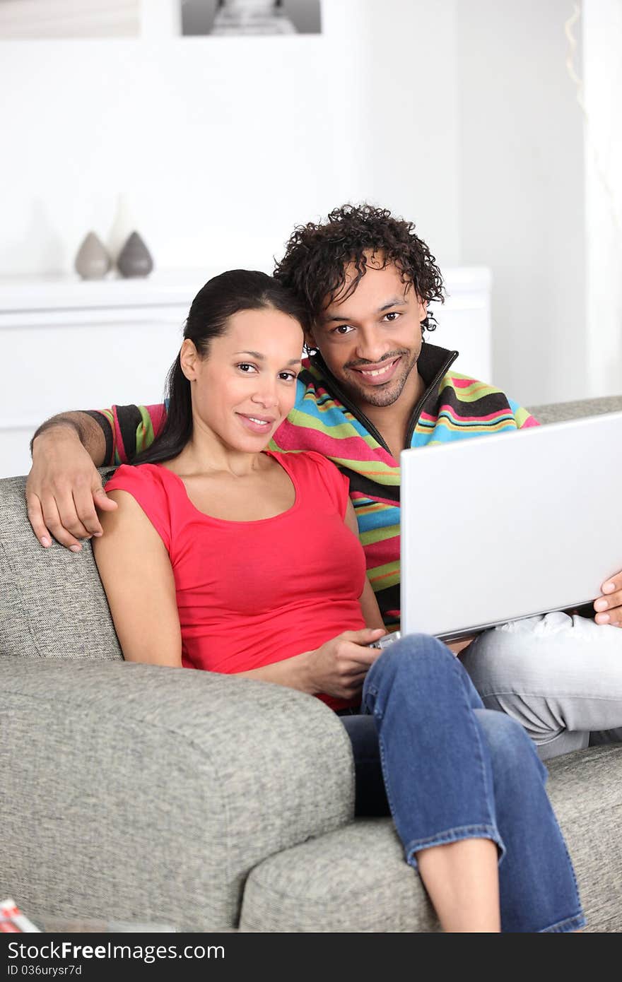 Smiling couple on a sofa with laptop