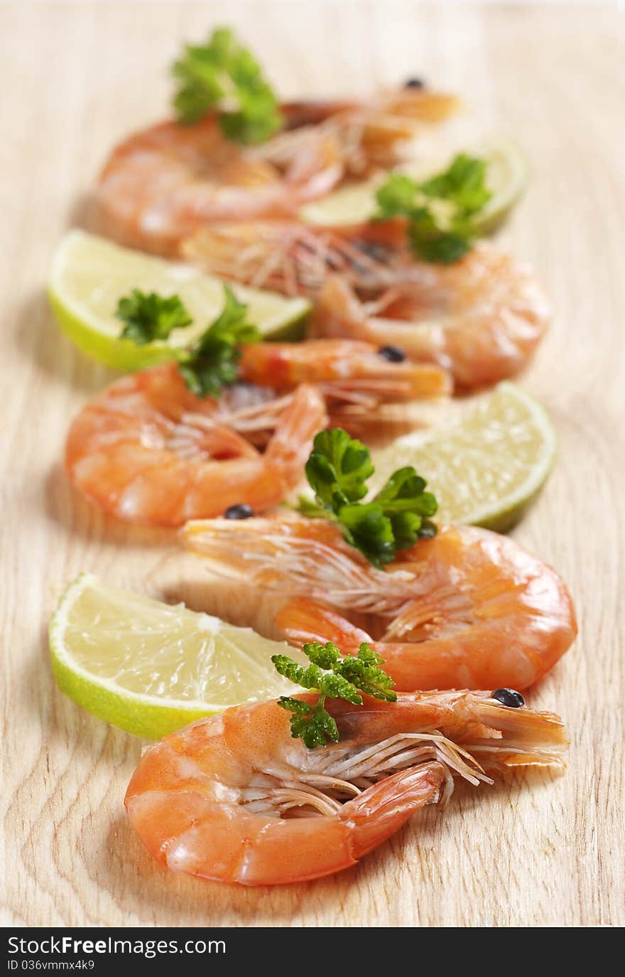 Shrimps on board with parsley and lemon wedges. Shrimps on board with parsley and lemon wedges