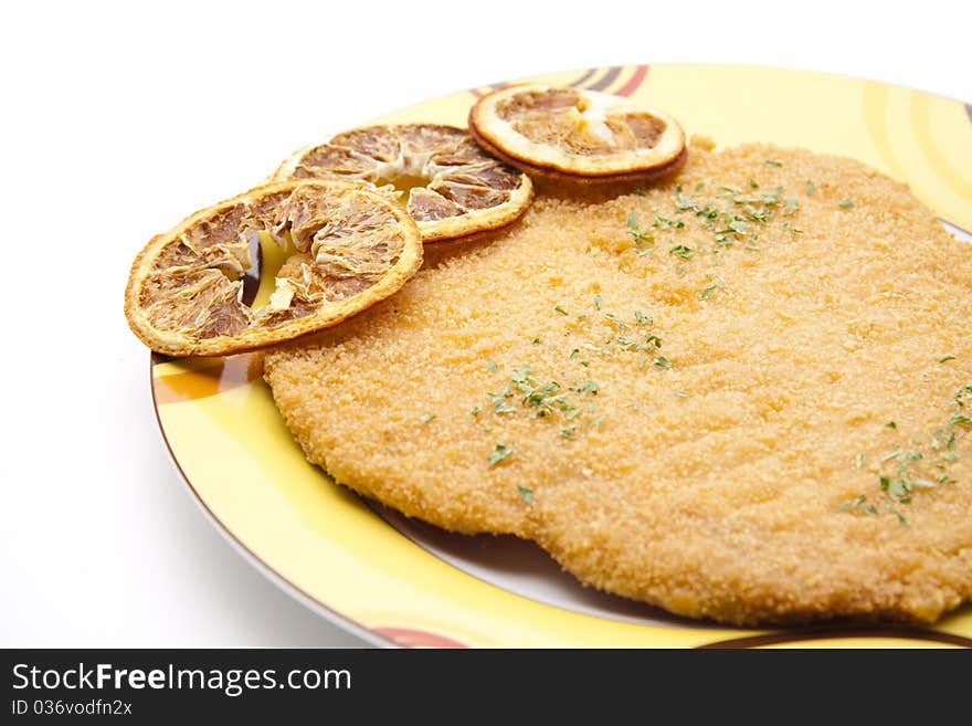 Escalope raw and breaded with lemon onto plates. Escalope raw and breaded with lemon onto plates