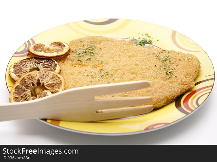 Escalope raw and breaded with lemon onto plates. Escalope raw and breaded with lemon onto plates