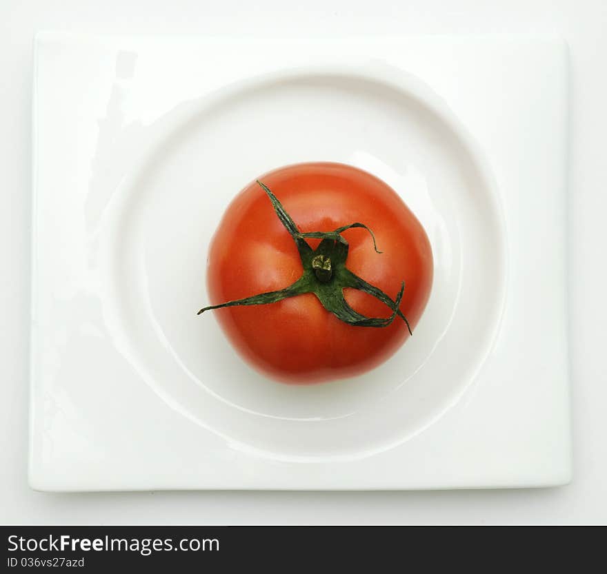 Tomato on white plate from top view. Tomato on white plate from top view.