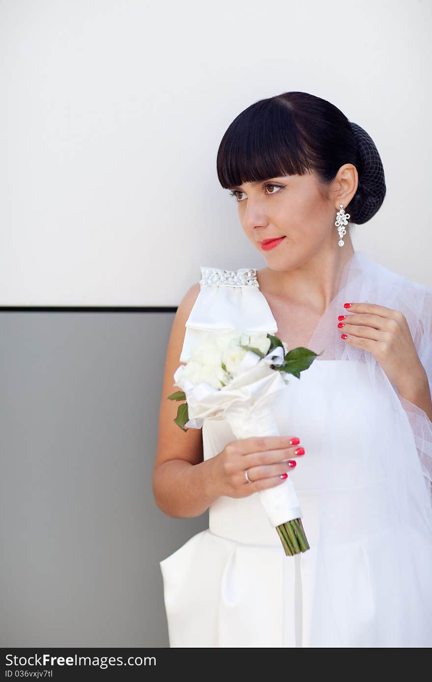 Bride with white roses near the wall