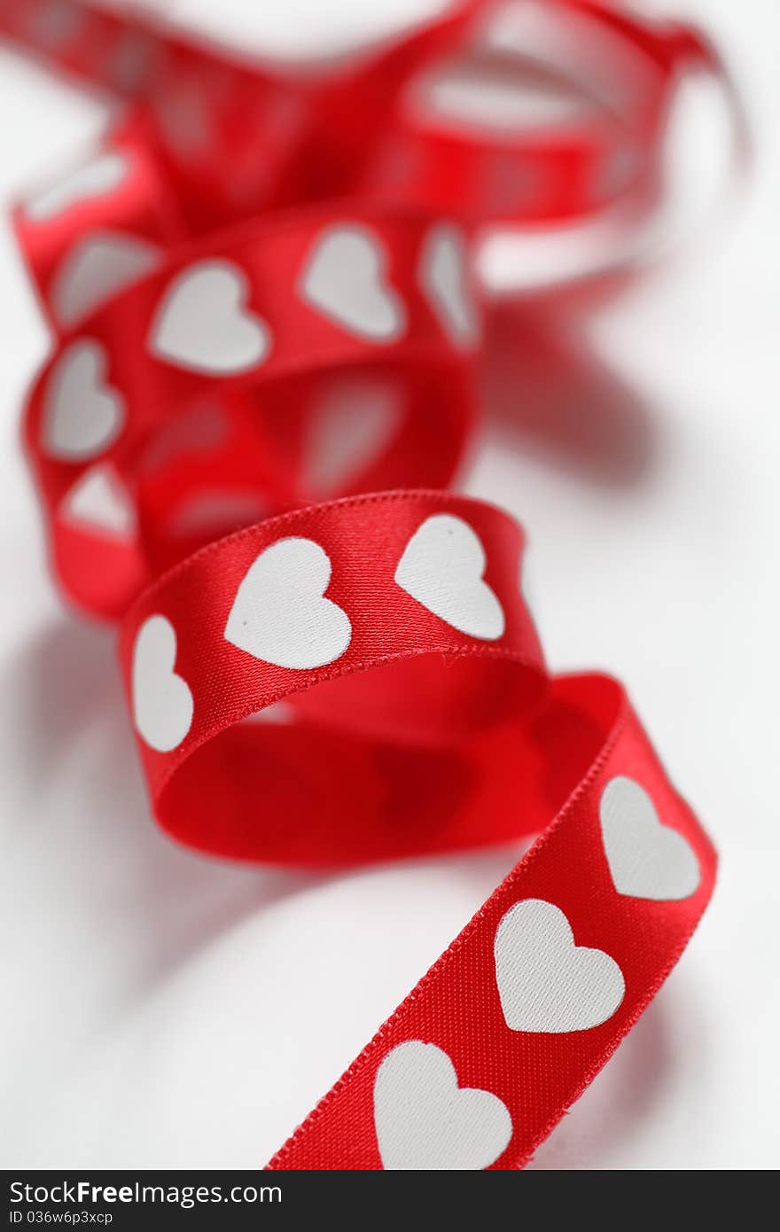 Red hearts ribbon curled in white