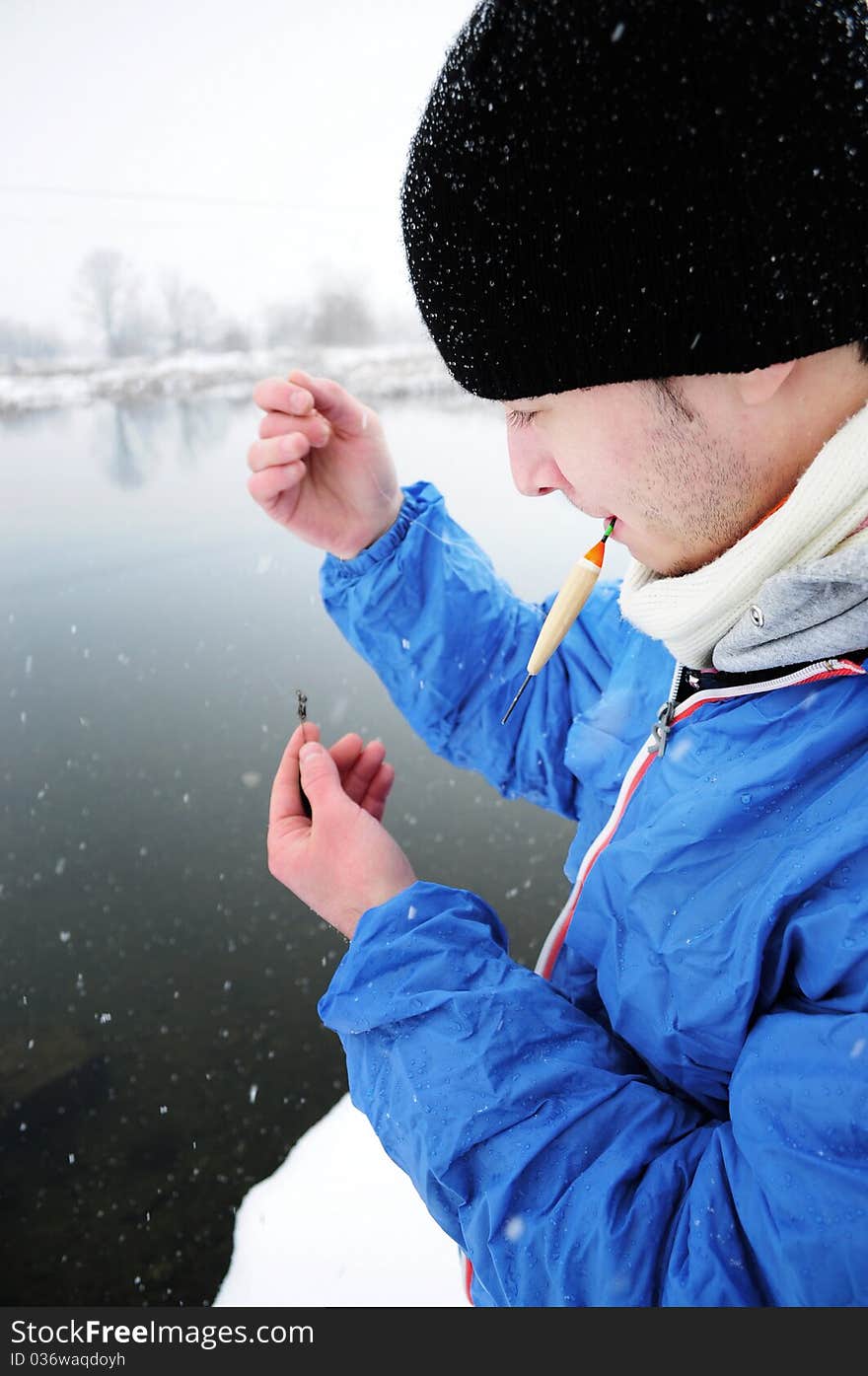 Image of a young fisherman preparing his fishing rod in winter time. Image of a young fisherman preparing his fishing rod in winter time