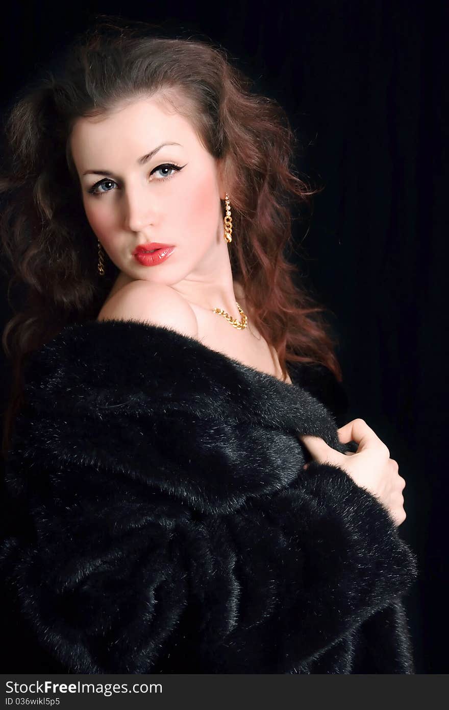 Beautiful young woman in a black fur coat and jewelry. Beautiful young woman in a black fur coat and jewelry