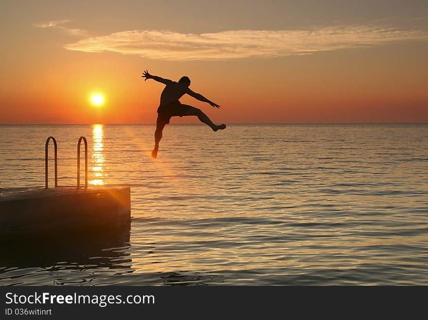 A man jumping into sea at sunset. A man jumping into sea at sunset