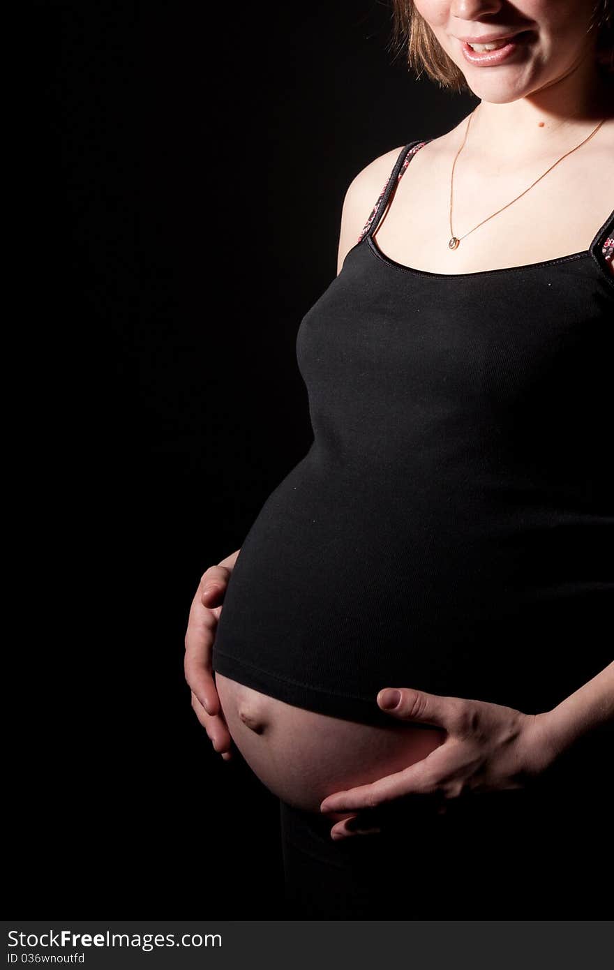 Beautiful pregnant woman staing on black background