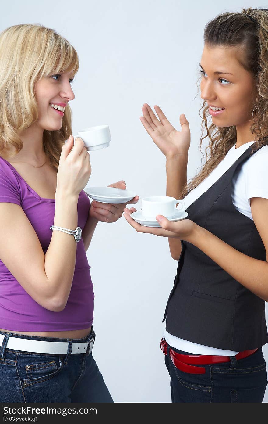 Two young beautiful girls to talk with a cup of coffee. Two young beautiful girls to talk with a cup of coffee