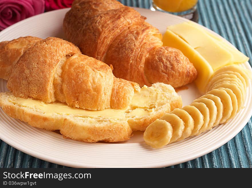 Breakfast plate with freshly baked croissants with butter, cheese and sliced bananas. Breakfast plate with freshly baked croissants with butter, cheese and sliced bananas