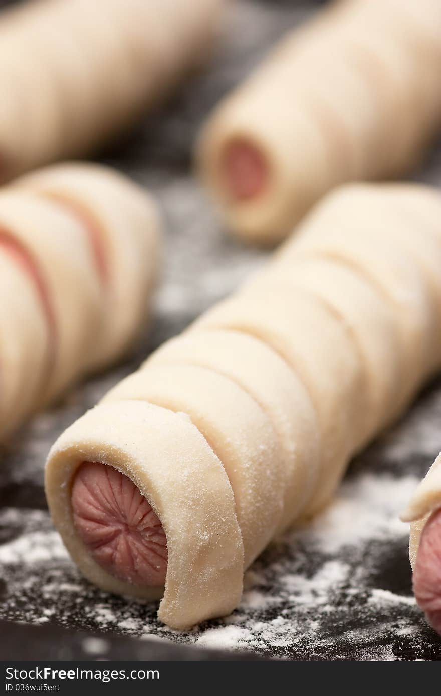 Raw sausage rolls in pastry on a baking tray