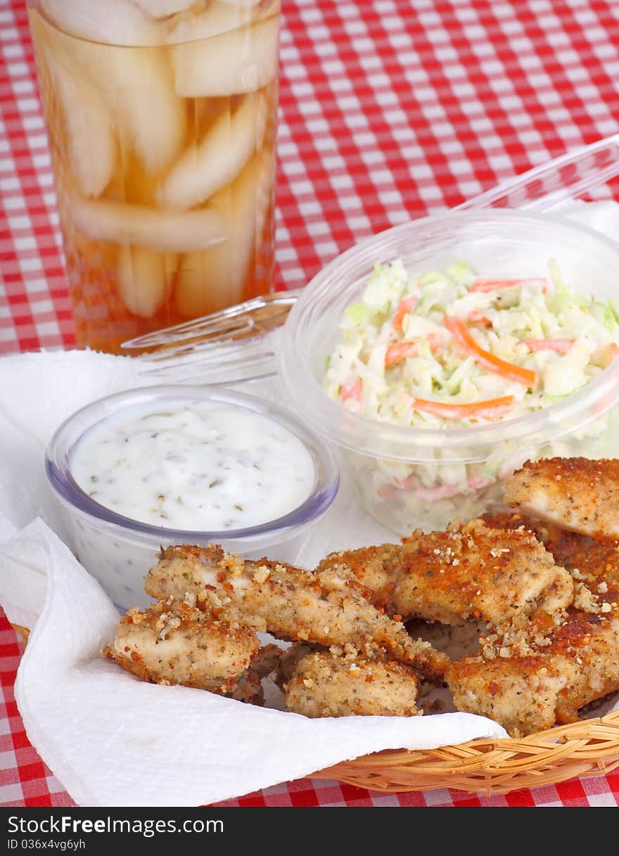 Chicken strips with coleslaw and sauce in a basket with a drink