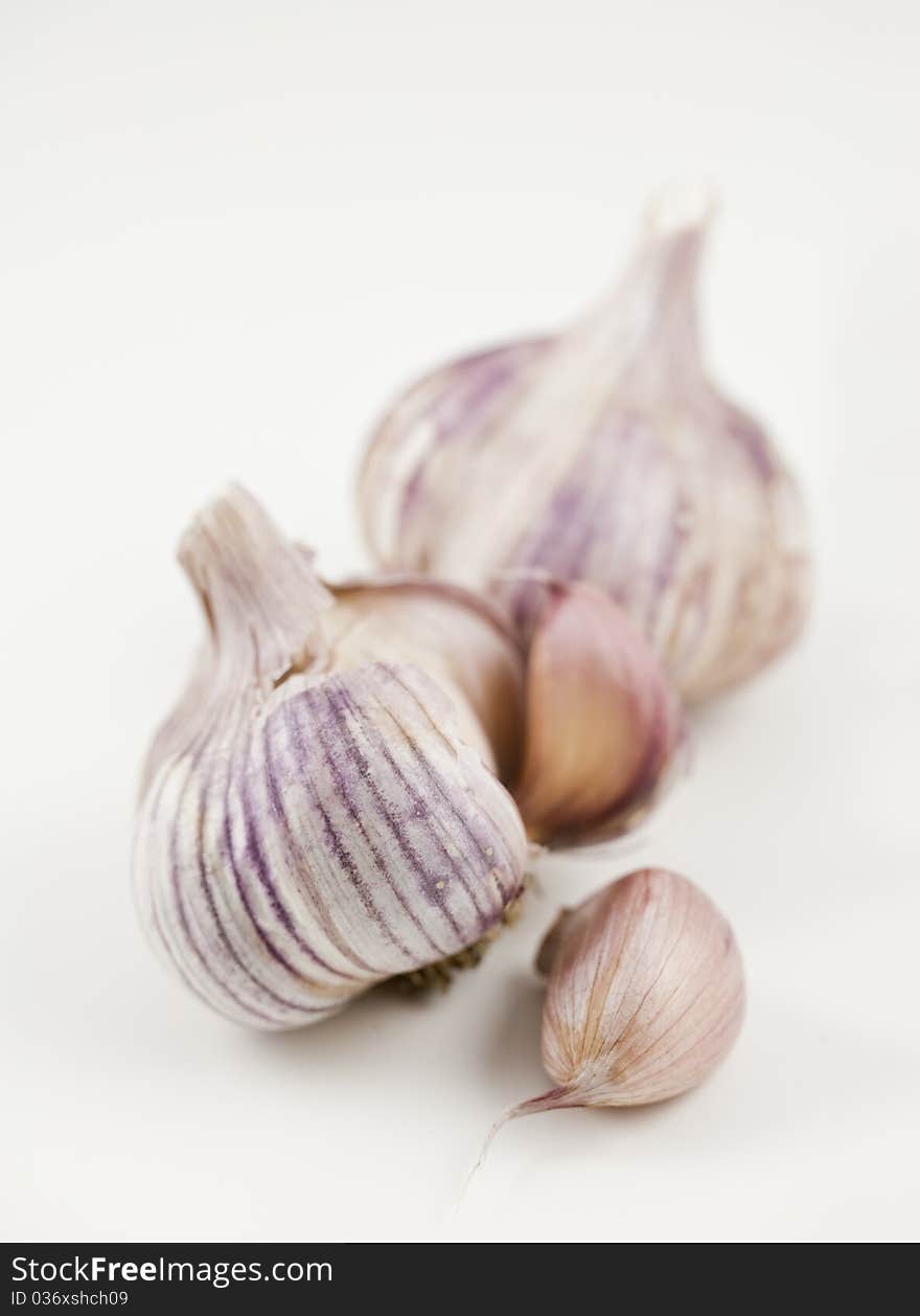 A garlic clove beside two heads of garlic, one open. Shallow depth of field. A garlic clove beside two heads of garlic, one open. Shallow depth of field.