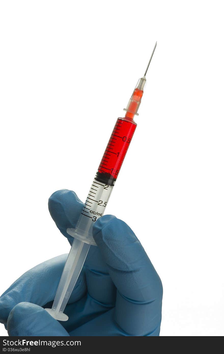 Isolated syringe with blue gloved hand holding it. Isolated syringe with blue gloved hand holding it