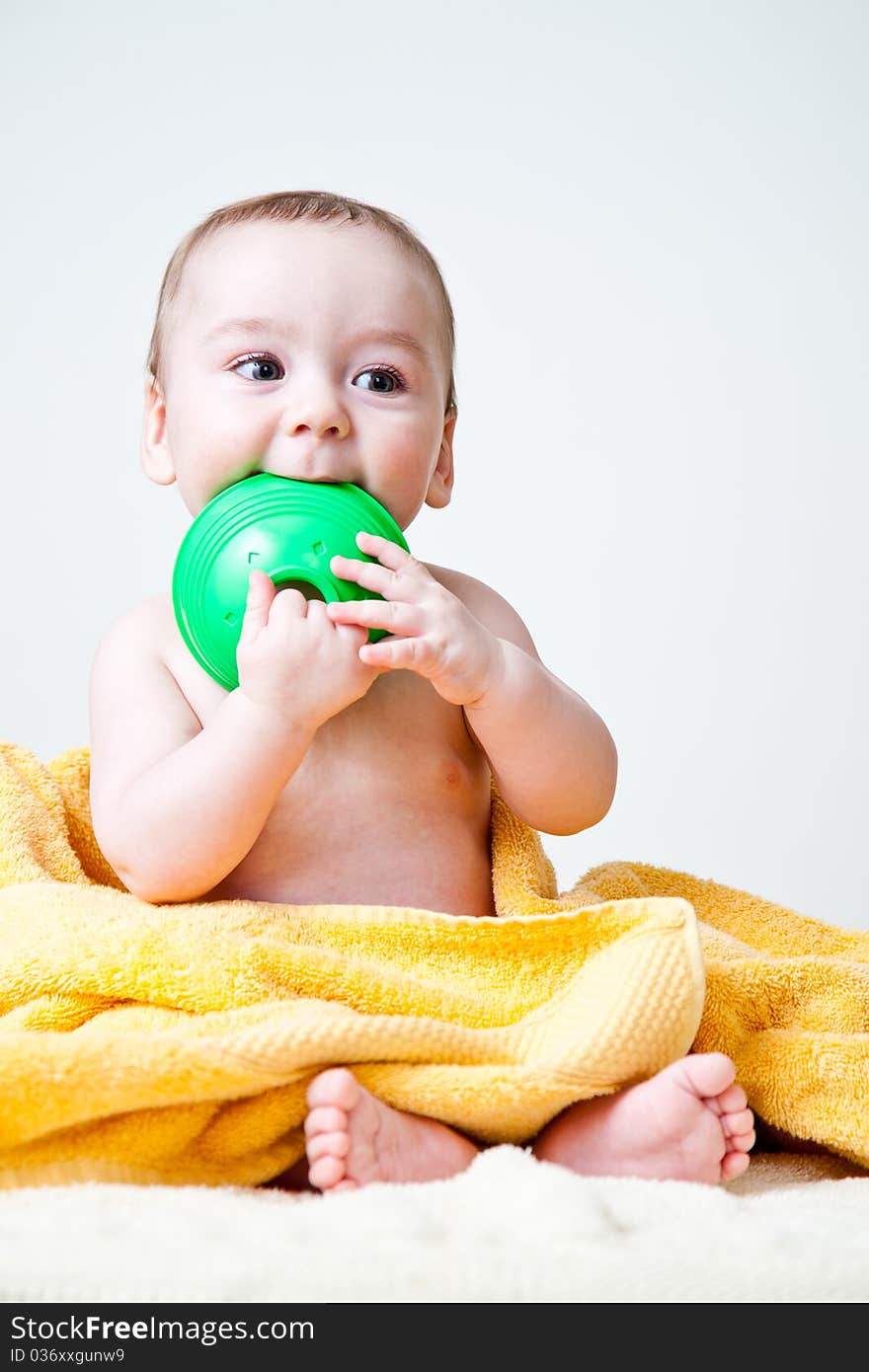 Baby Gnawing Green Toy On Yellow Towel