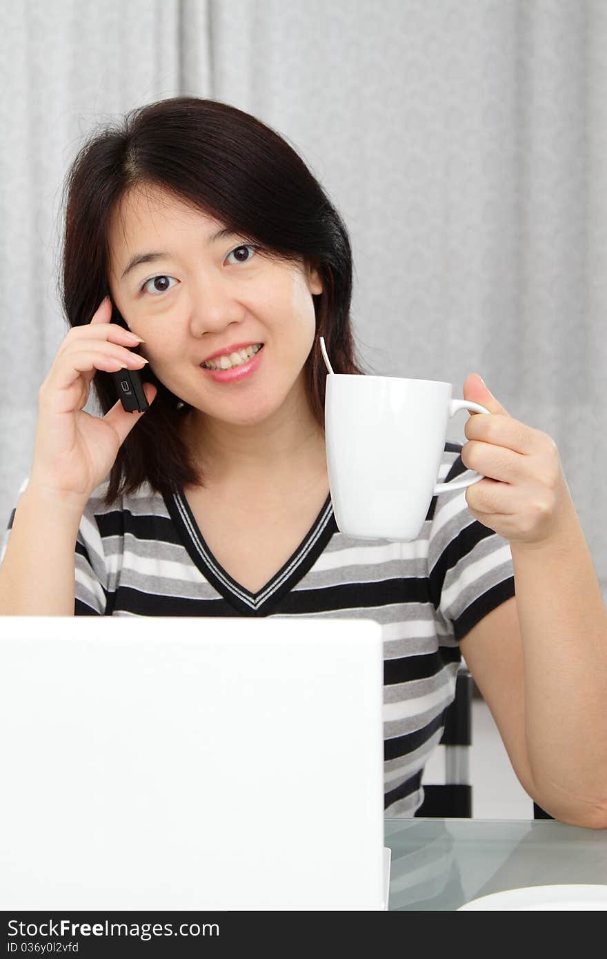 An Asian woman holding a cup of coffee while working. An Asian woman holding a cup of coffee while working