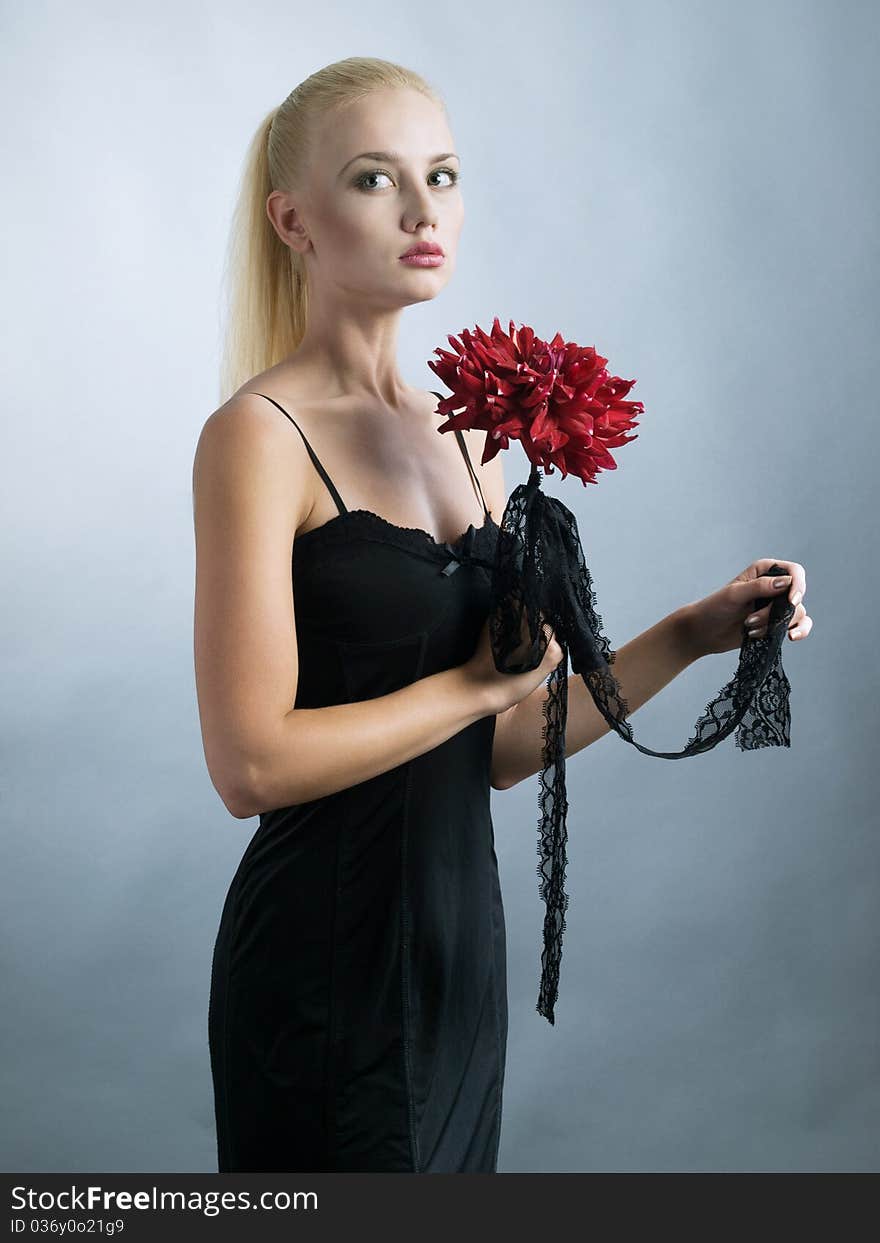 Elegant blonde girl in black dress and red flower at hand. Elegant blonde girl in black dress and red flower at hand