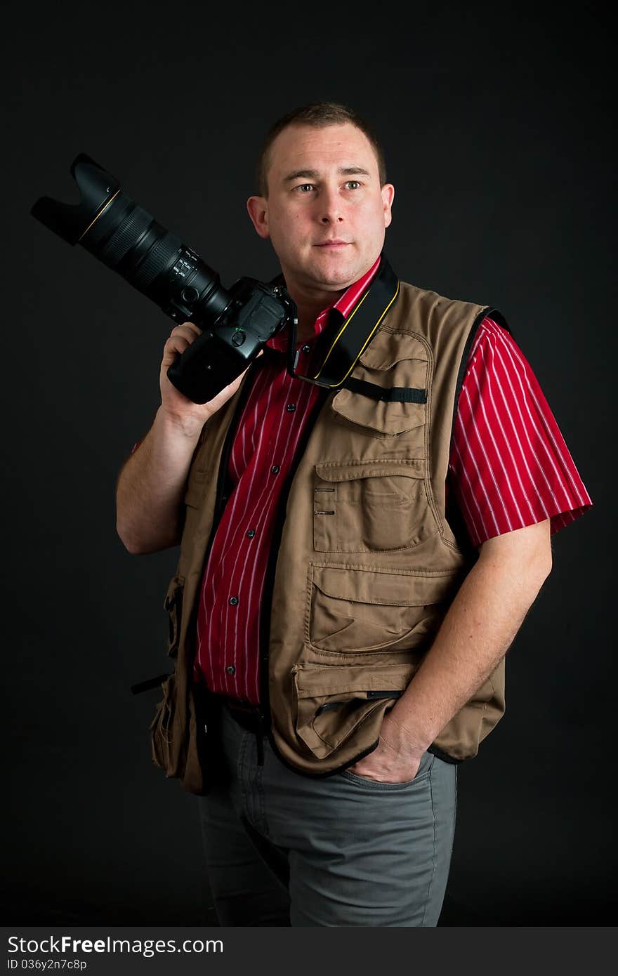 Photographer with digital kamera and zoom lens on dark background