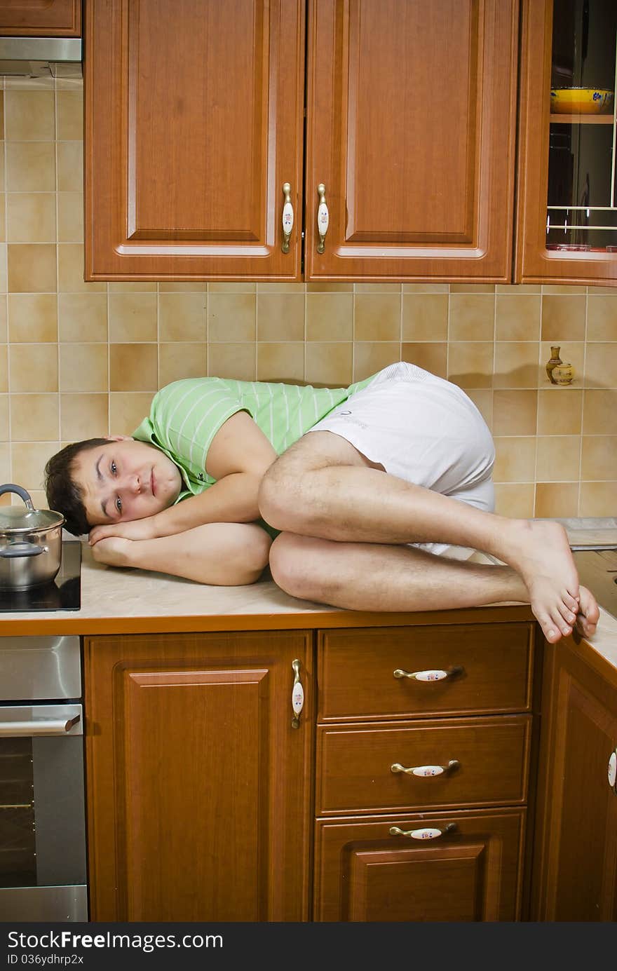 Young handsome guy lying on the kitchen table. Young handsome guy lying on the kitchen table