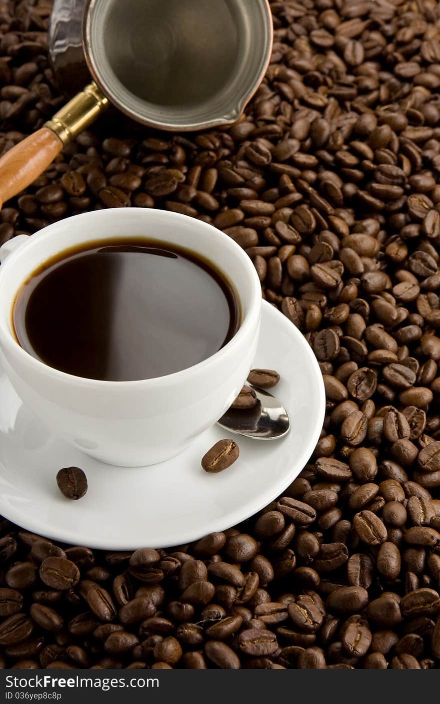 Cup of coffee and pot on beans as background