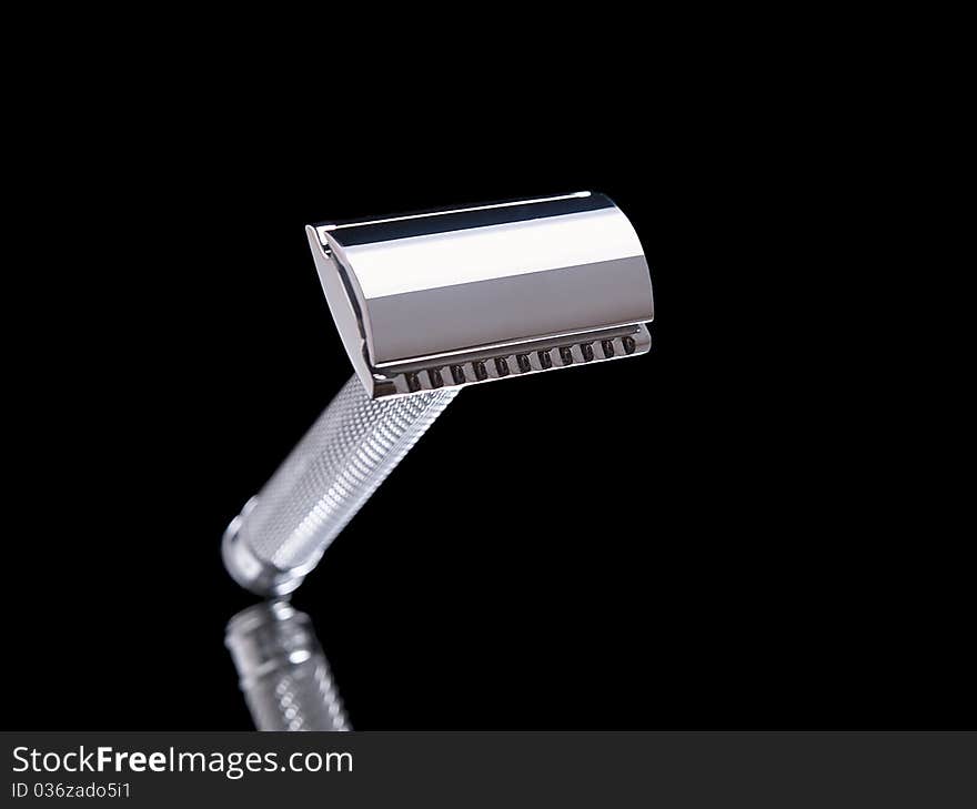 The image shows a razor over a reflective black background