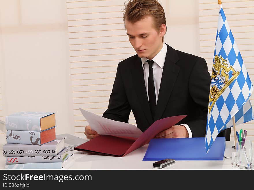 Handsome blond man sitting at his desk and studying some papers. Handsome blond man sitting at his desk and studying some papers