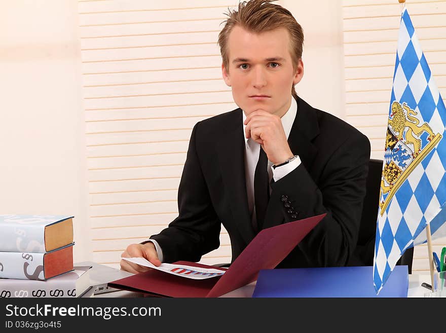 Handsome blond man sitting at his desk and studying some papers. Handsome blond man sitting at his desk and studying some papers