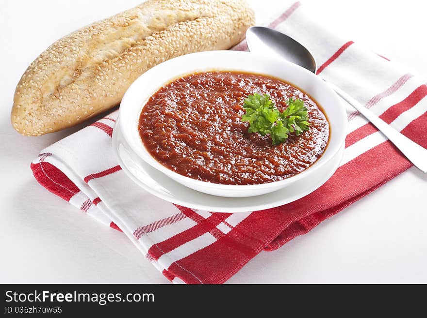 Tomato soup with parsley in a bowl on white background