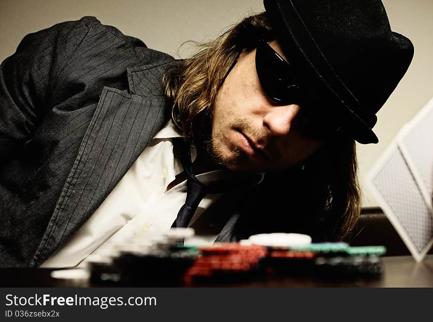 Man with hat and glasses playing underground poker. Man with hat and glasses playing underground poker.