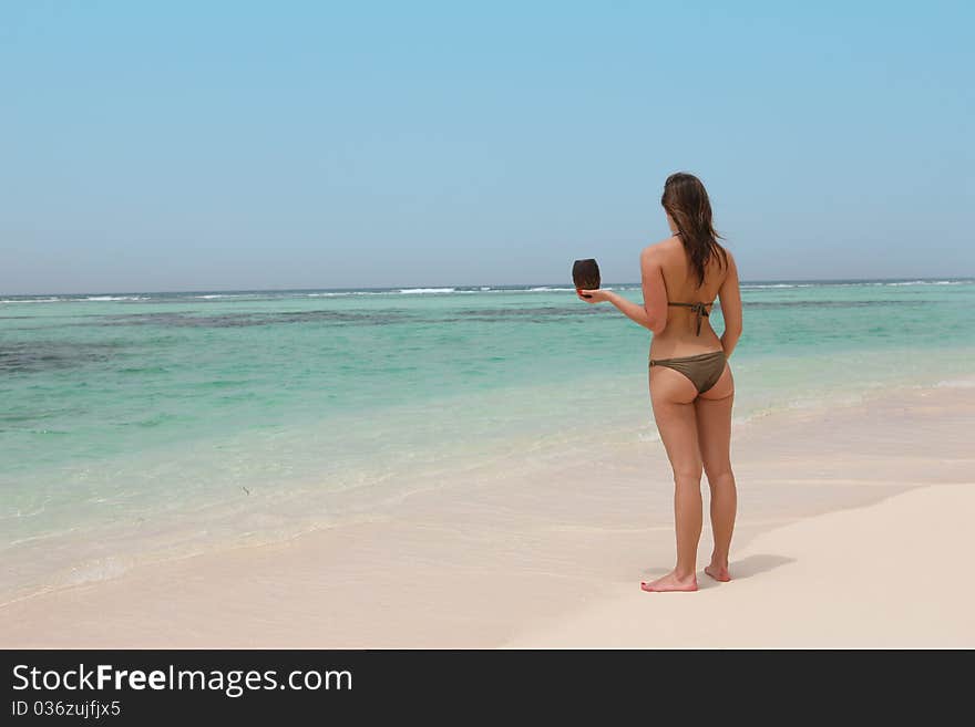 Beautiful woman in a tropical beach holding a coconut