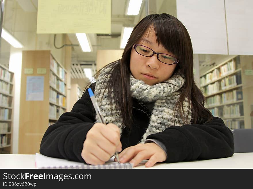 An Asian girl who is reading and studying