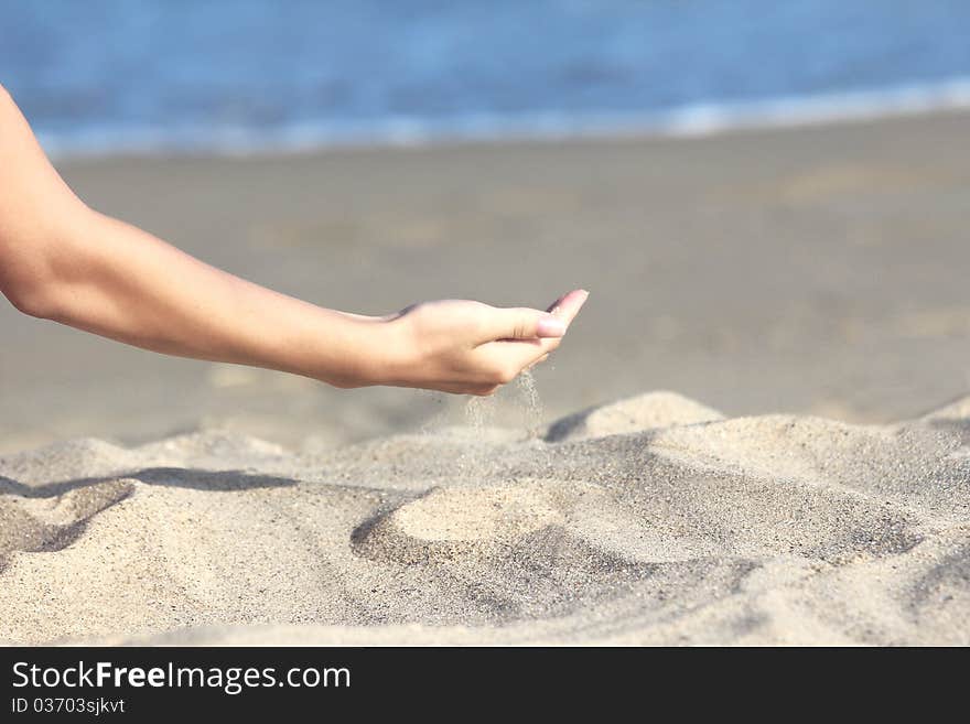 Hand pour sand on the seashore