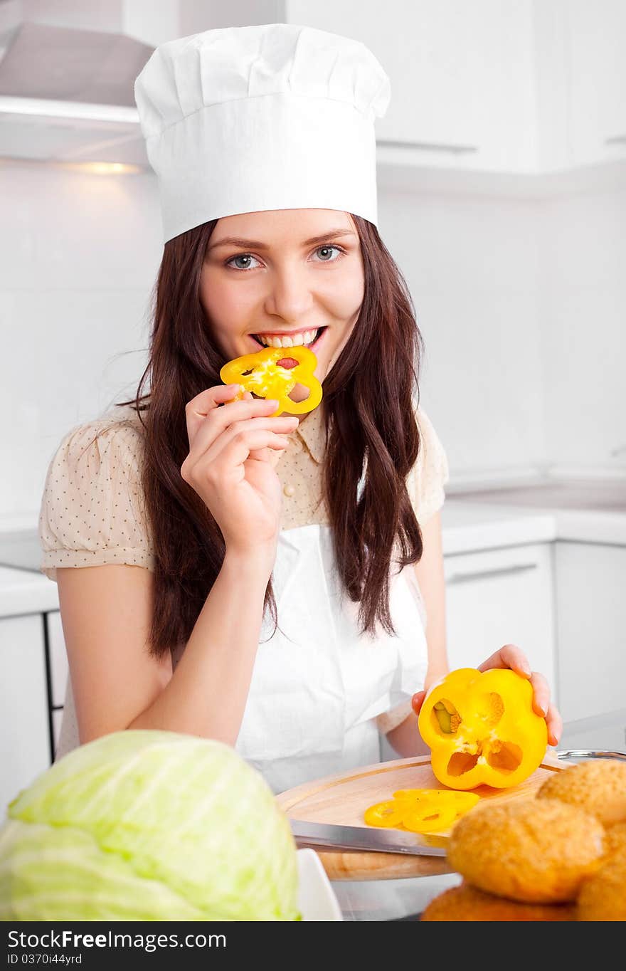 Beautiful young cook with vegetables in the kitchen