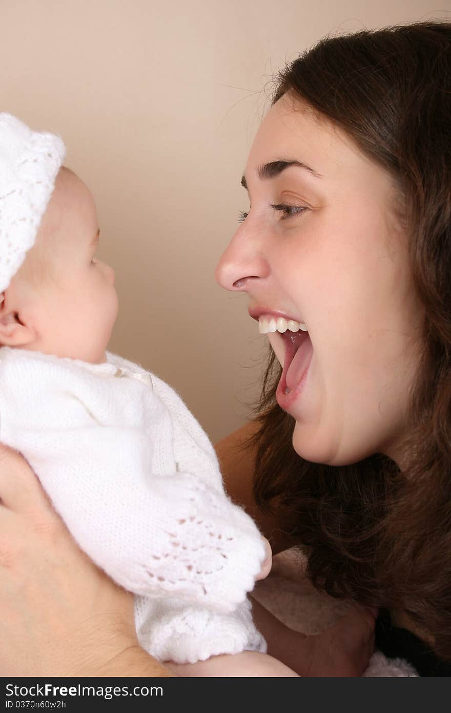 Beautiful brunette mother looking at her two month old baby girl. Beautiful brunette mother looking at her two month old baby girl