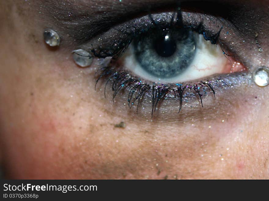 A blue eye with gems in corners and dirt on the face. A blue eye with gems in corners and dirt on the face