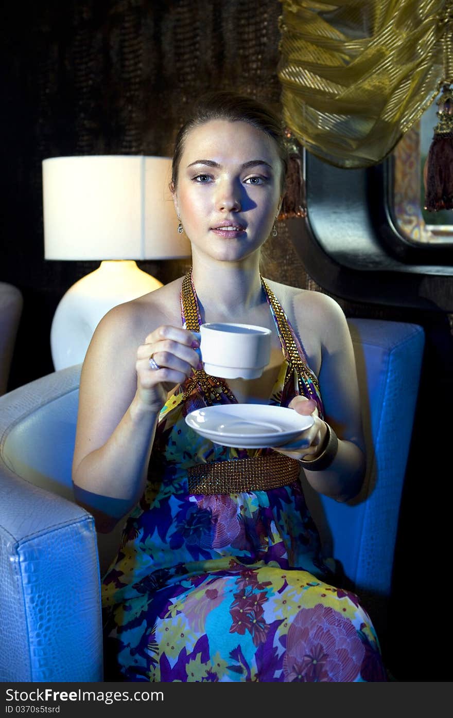 Young beautiful woman sitting on armchair and drinking tea in restaurant. Young beautiful woman sitting on armchair and drinking tea in restaurant