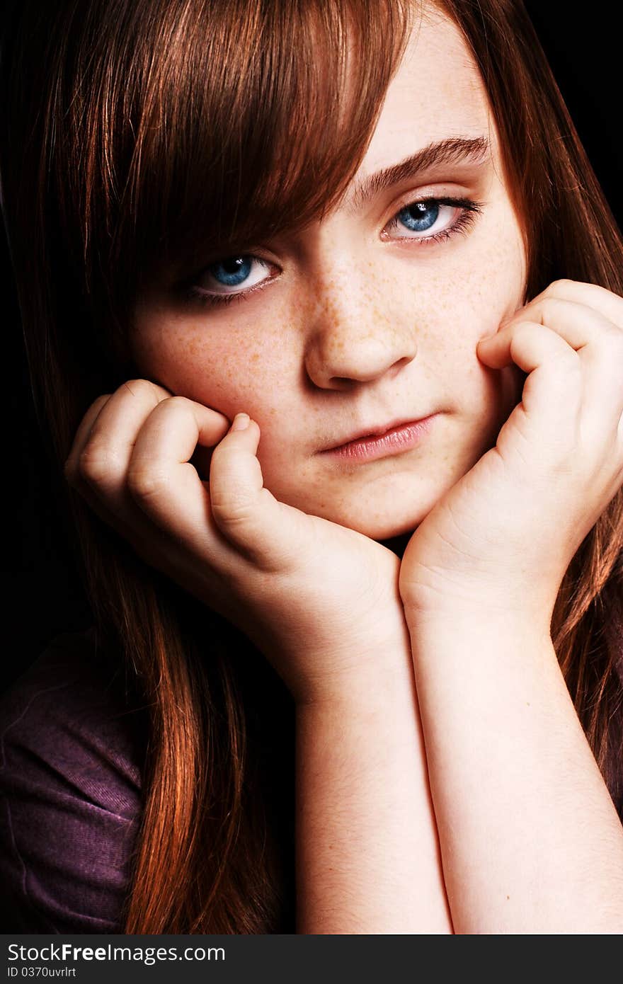 A beautiful young girl looking at the camera on a black background. A beautiful young girl looking at the camera on a black background.