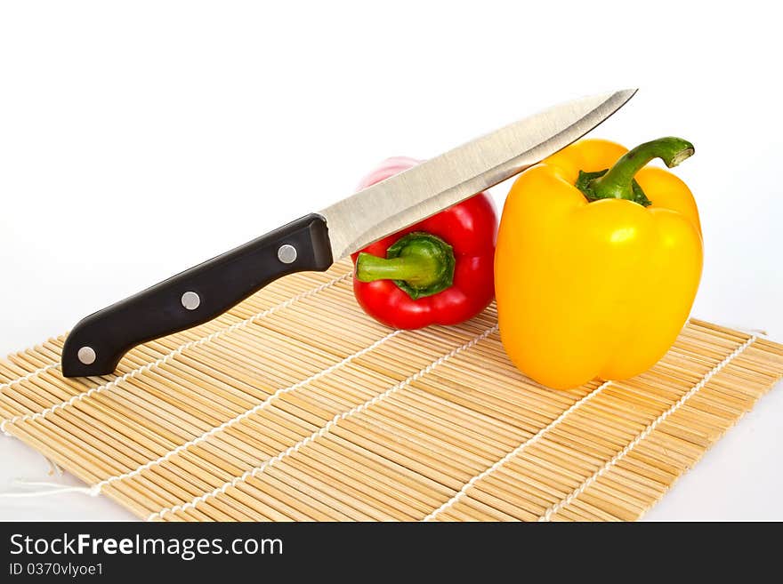 A knife on yellow and red sweet peppers isolated on a white background