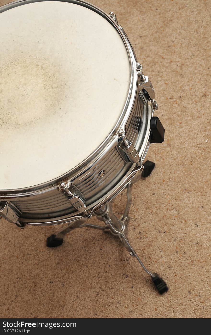 Above view of a snare drum on a stand on a carpet.