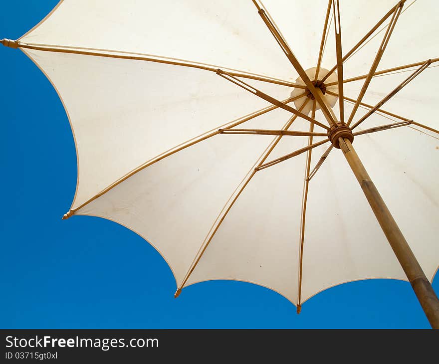 Under a white bamboo umbrella bright sky. Under a white bamboo umbrella bright sky